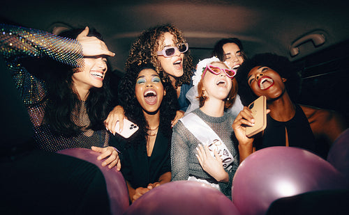 Group of friends in the back of a taxi singing and celebrating a bachelorette party