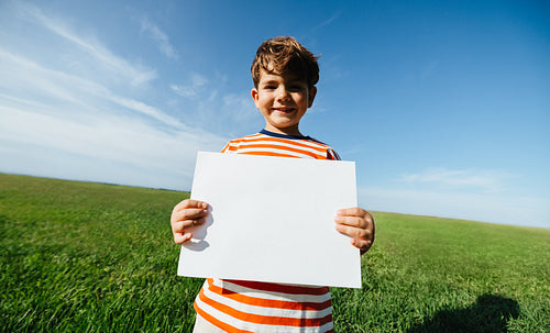 Young boy holds blank sign outdoors