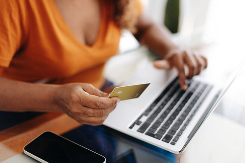 Woman using a gold credit card to make an online purchase with a laptop