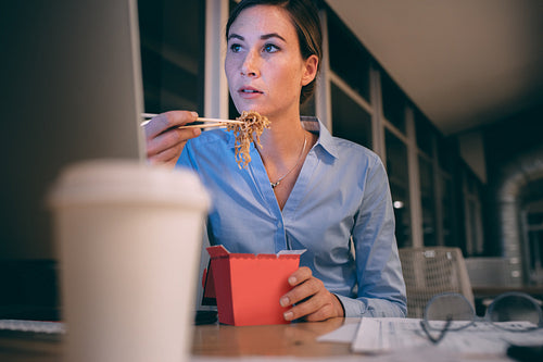 Businesswoman having food while working late in office