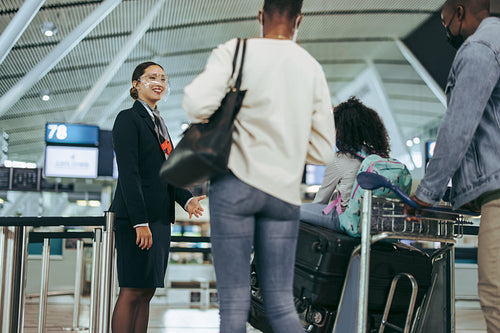 Ground attendant in pandemic welcoming tourist family at airport