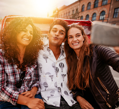 Cheerful teenagers taking selfie on tricycle