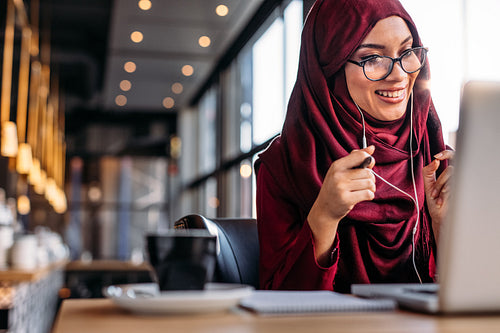 Muslim woman having a video chat on laptop at cafe