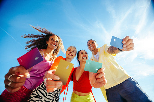 Young adults celebrate financial independence with colorful cards outdoors