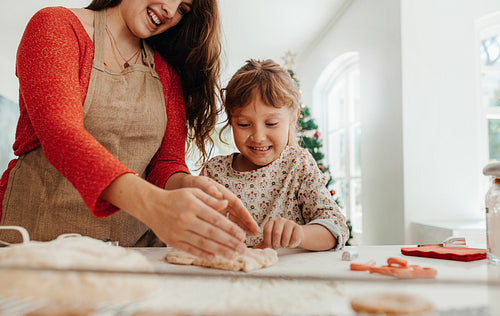 Mother teaching daughter to make cookies for Christmas.