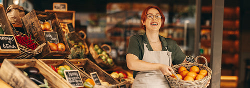 Successful grocery store owner holding a basket of fresh organic fruits