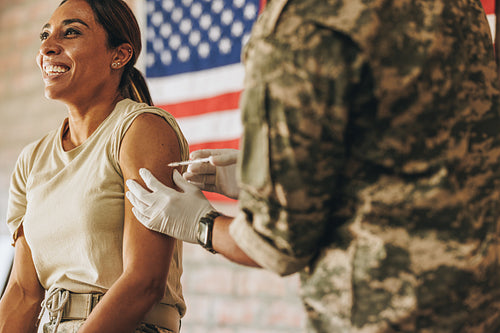 Ethnic female soldier getting inoculated in the military hospita