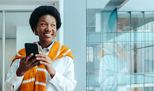 Successful black female entrepreneur smiling confidently while looking through a glass window
