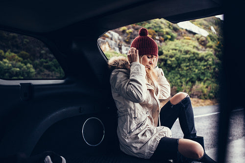 Beautiful woman sitting relaxed in car trunk