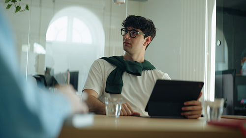 Man speaks during a business meeting in a bright office with tablet at the table