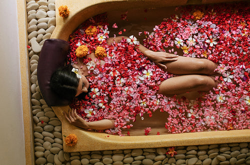Woman in bathtub with petals