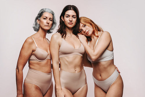 Three women standing close and embracing in studio