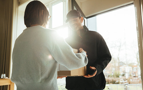 Woman receives a package from a courier at an office entrance