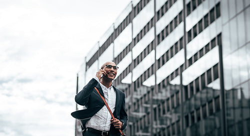 Businessman talking on mobile phone walking outdoors