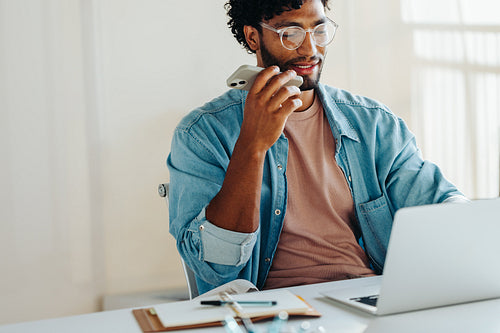 Focused business man having a phone call discussion while working with a laptop in a modern office