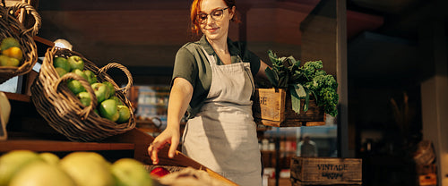 Cheerful grocery store owner restocking fresh produce in her shop