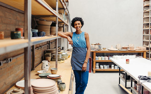 Happy young ceramist smiling at the camera in her pottery
