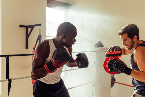 Boxing instructor training a young fighter in a gym