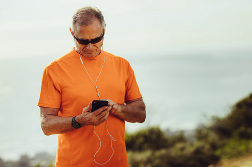 Athletic senior man listening to music during workout