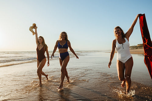 Three women enjoying sunset at the beach during a summer holiday