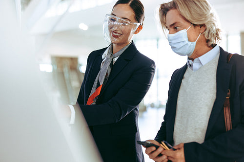 Flight attendant assisting traveler with self check in at airpor