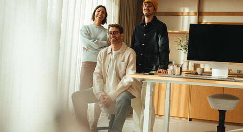Coworkers smile in office for a team portrait at the desk