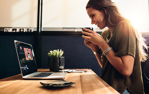 Young female vlogger watching her vlog on computer.