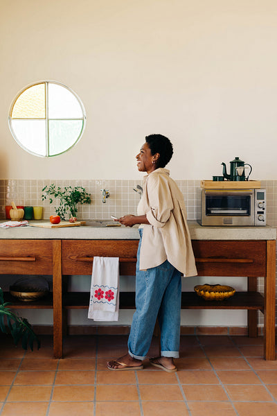 Happy black woman using a smartphone to browse recipe in a Brazilian kitchen