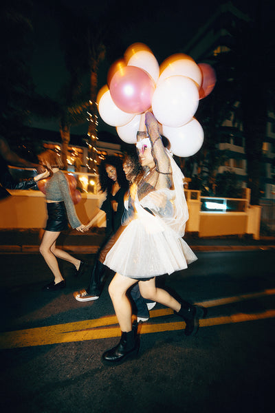 Group of friends celebrating at night outdoors with colorful balloons