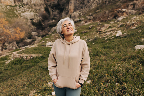Cheerful senior woman smiling while standing on a hiking trail o