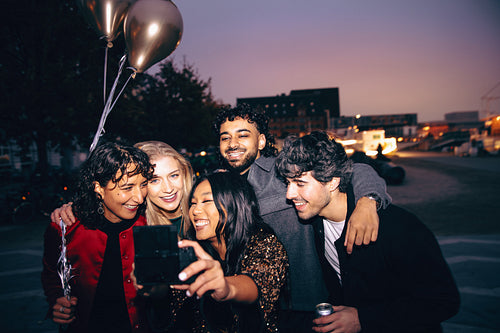 Smiling friends taking a selfie during a festive evening outdoors