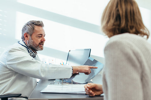 Doctor showing x-ray to patient in medical office