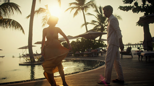 Romantic couple affectionately dancing together during a beautiful tropical sunset at a luxury resort