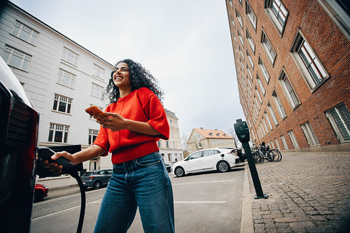 Clean city travel starts as a woman charges her car on the street