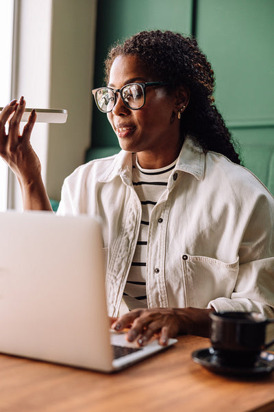 Happy Black woman smiling while recording voice message