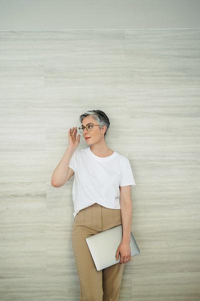 Businesswoman with eyeglasses standing against a wall