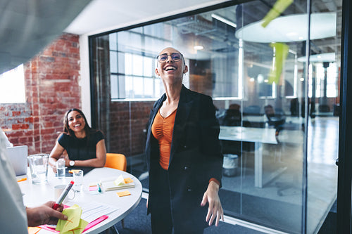 Two businesswomen sticking adhesive notes to a glass wall in an