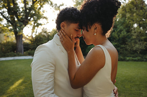 Newlywed couple embracing outdoors in warm sunlight