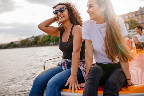 Friends relaxing on pedal boat in lake