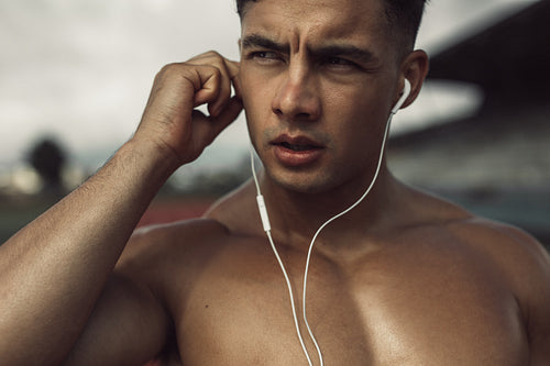 Muscular male athlete with earphones
