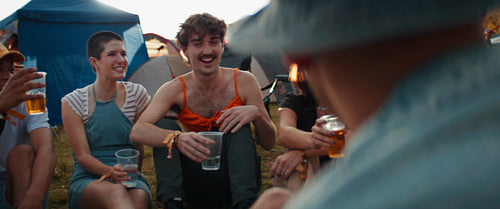 Happy young woman cheers friends at a festival campsite