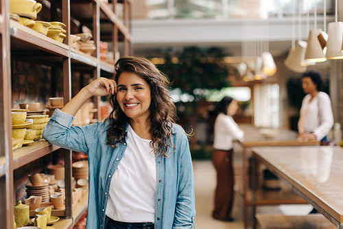 Happy young woman running a successful ceramic store