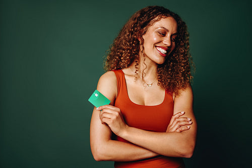 The woman presents a banking card with a confident smile in green