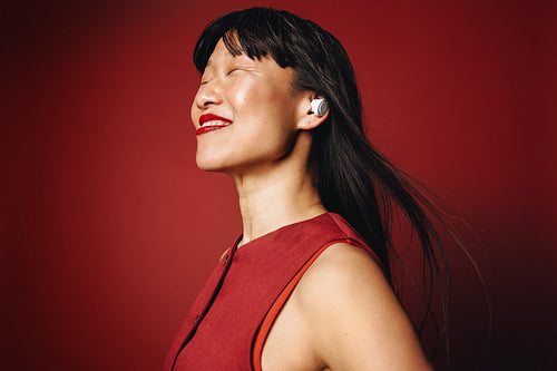 The woman relaxes with listening and earbuds in a red portrait