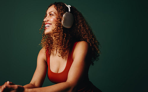 Woman wearing headphones listening to music and smiling in studio portrait