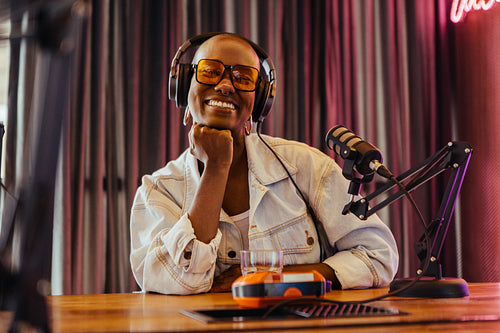 Happy female podcast host enjoying a recording session in a stylish studio environment