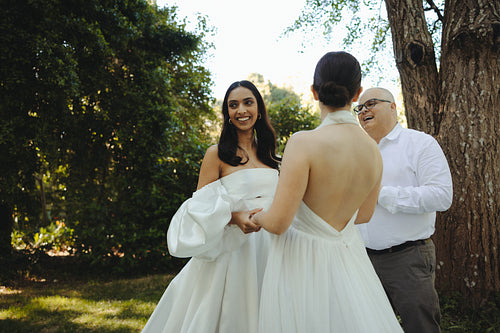 Outdoor wedding ceremony with two brides exchanging vows in a garden setting