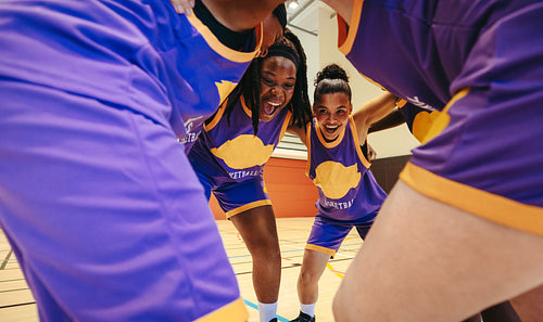 Female basketball team in group huddle sharing encouragement and unity