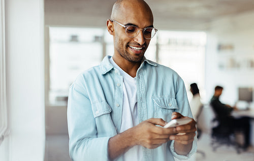 Business man sending a text on a mobile phone in an office