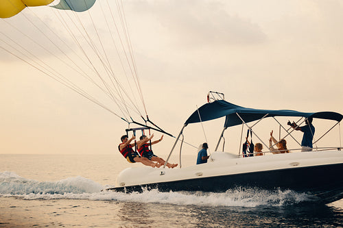 Group of people enjoying parasailing adventure over the ocean while being towed by a speedboat